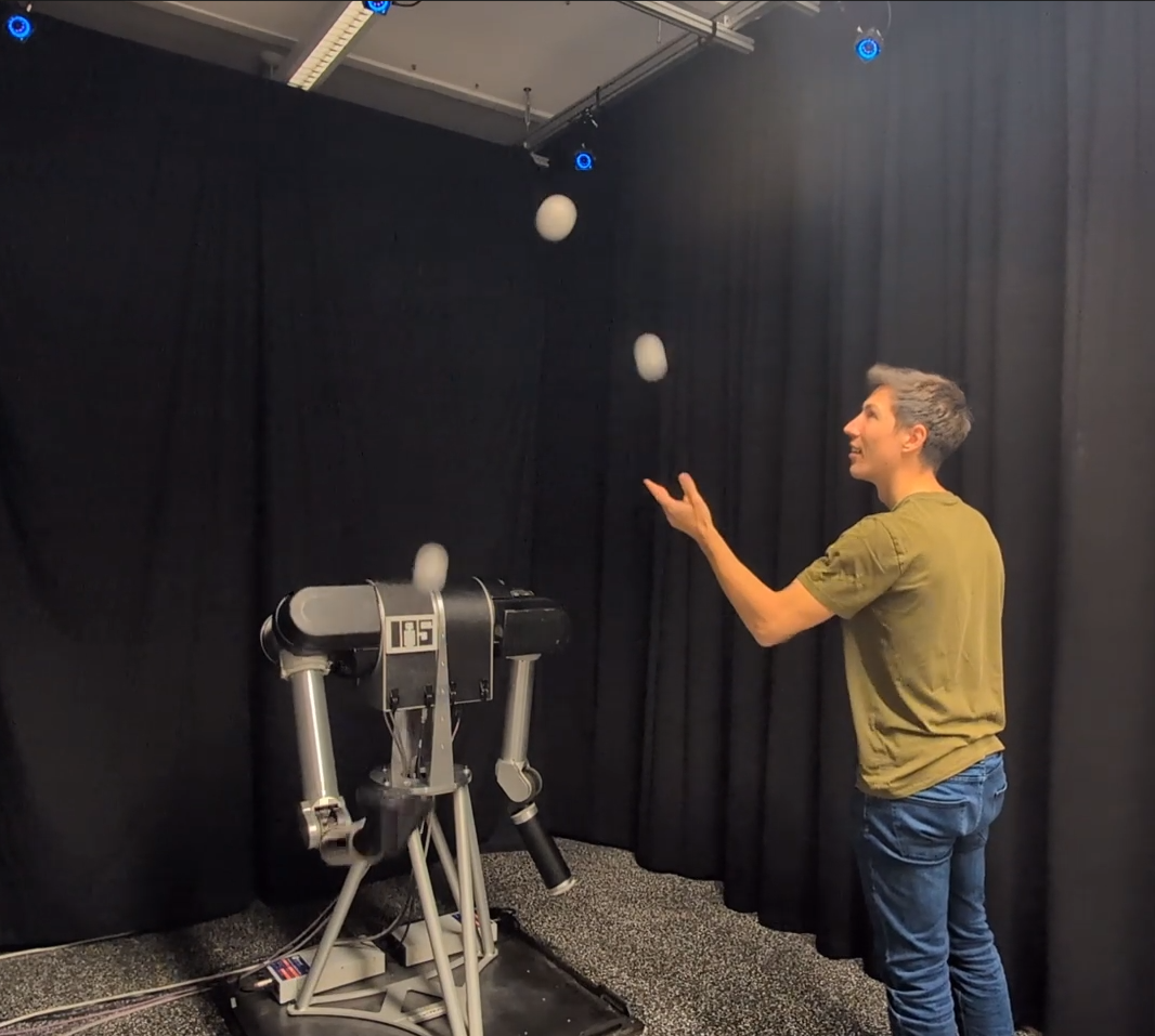 A human and a Barrett WAM robot arm exchanging juggling balls in a three-ball cascade pattern.